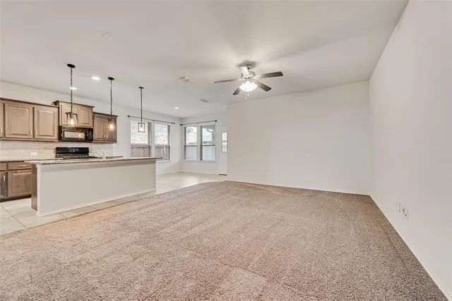 an empty room with chandelier fan and windows