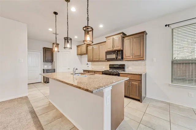 a kitchen with stainless steel appliances granite countertop a sink a stove and a wooden cabinets
