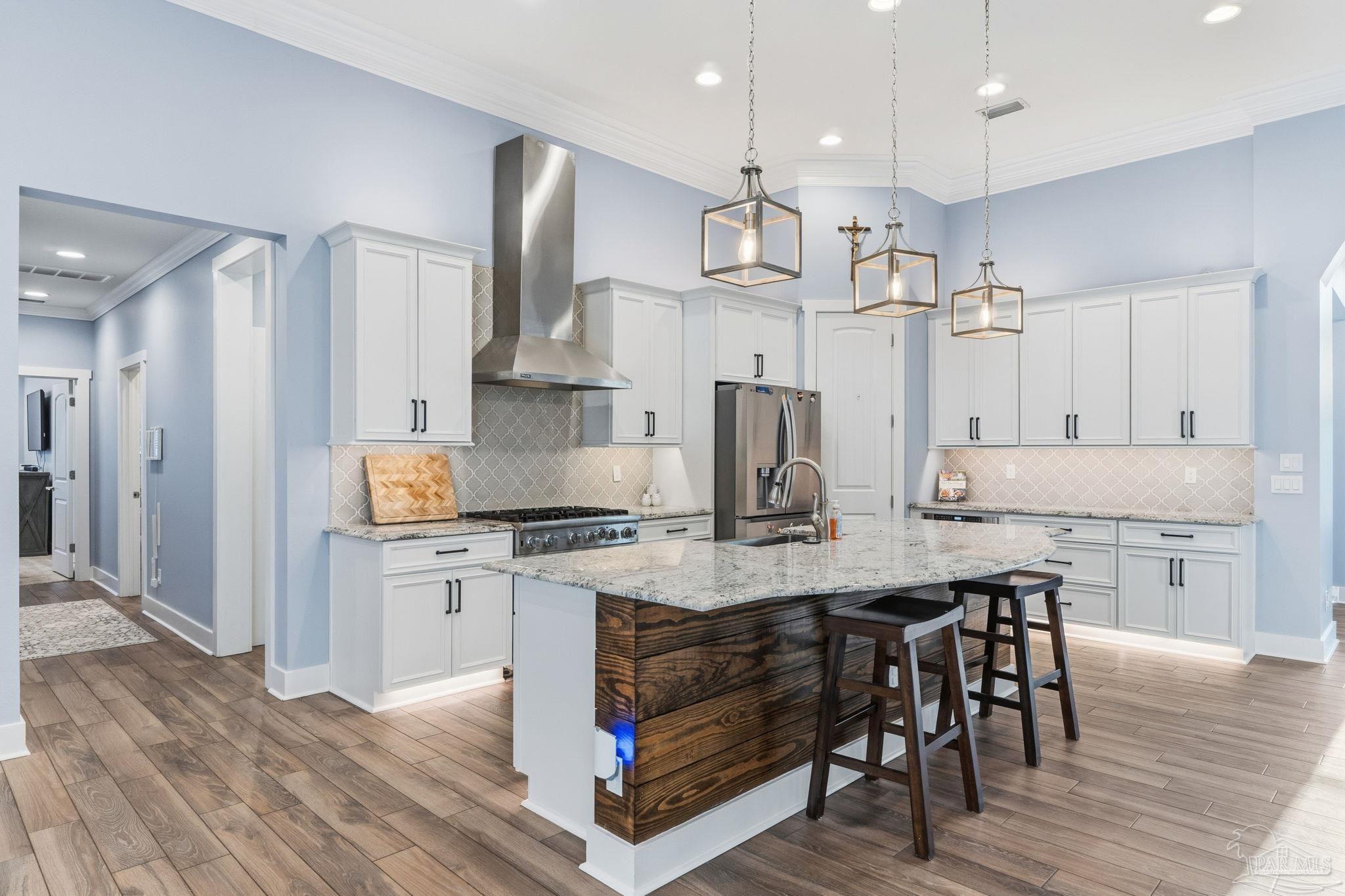 2018 Rambling Oaks Drive Cantonment, FL 32533 - Photo 23 of 64 a kitchen with stainless steel appliances granite countertop a stove a refrigerator a kitchen island a sink and white cabinets with wooden floor