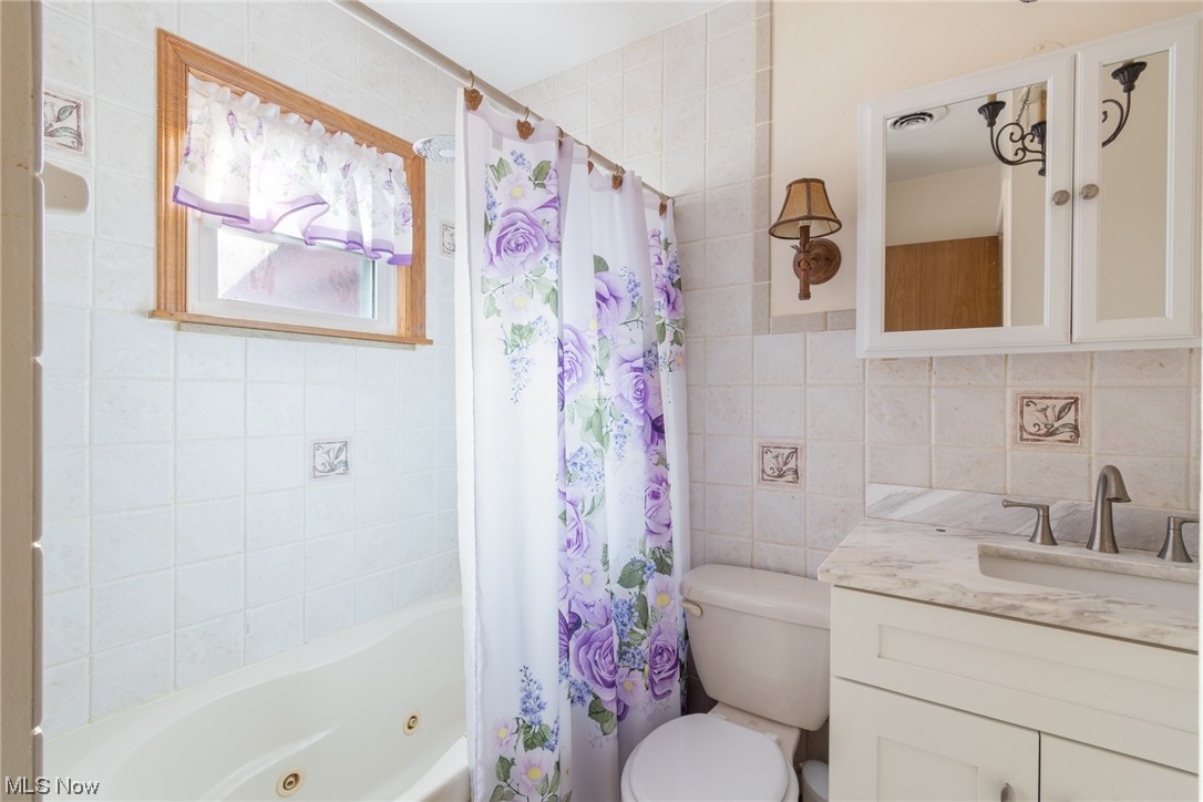 4433 Burkey Road Youngstown, OH 44515 - Photo 17 of 28 Full bathroom featuring tile walls, mirror, shower / bathtub combination with curtain, and vanity