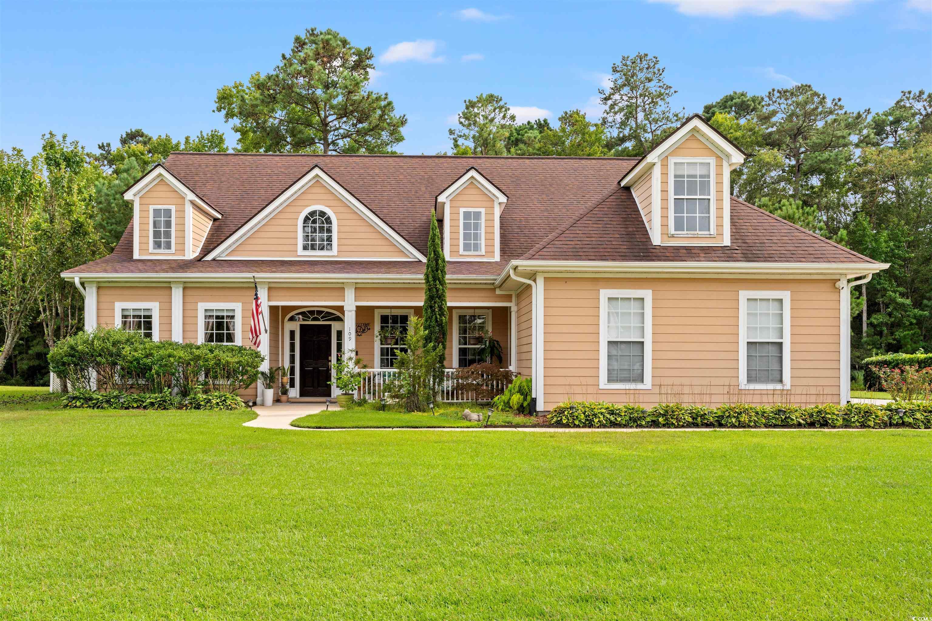View of front of house with covered porch, a front lawn, and a shingled roof