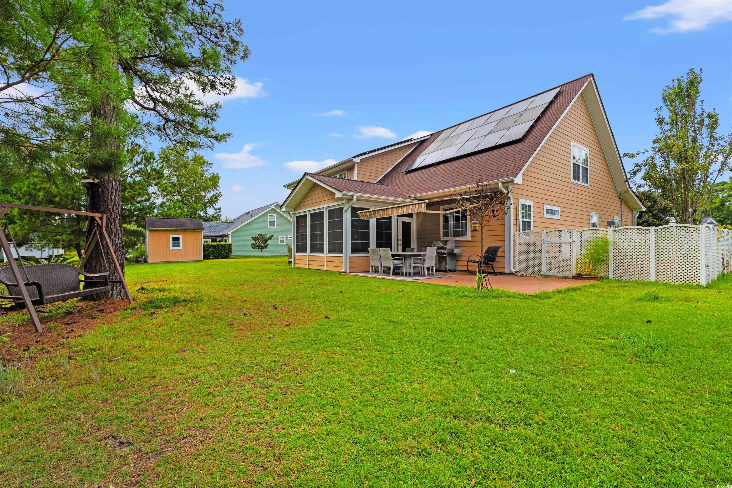 109 Eden Court Murrells Inlet, SC 29576 - Photo 26 of 31 Rear view of house featuring roof mounted solar panels, a patio, a sunroom, a storage shed, and roof with shingles