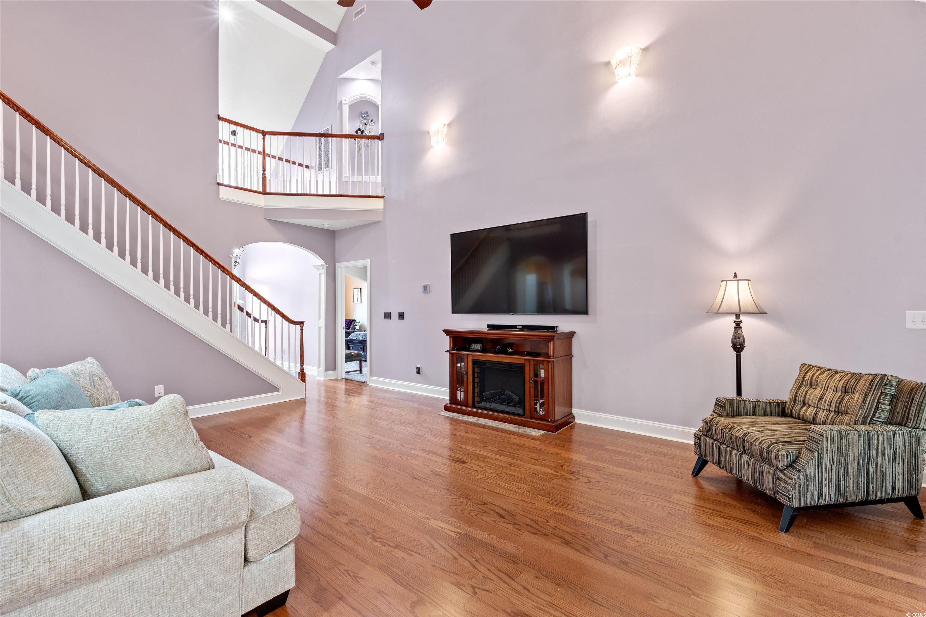 109 Eden Court Murrells Inlet, SC 29576 - Photo 3 of 31 Living room with arched walkways, light wood-style flooring, stairway, a towering ceiling, and a fireplace