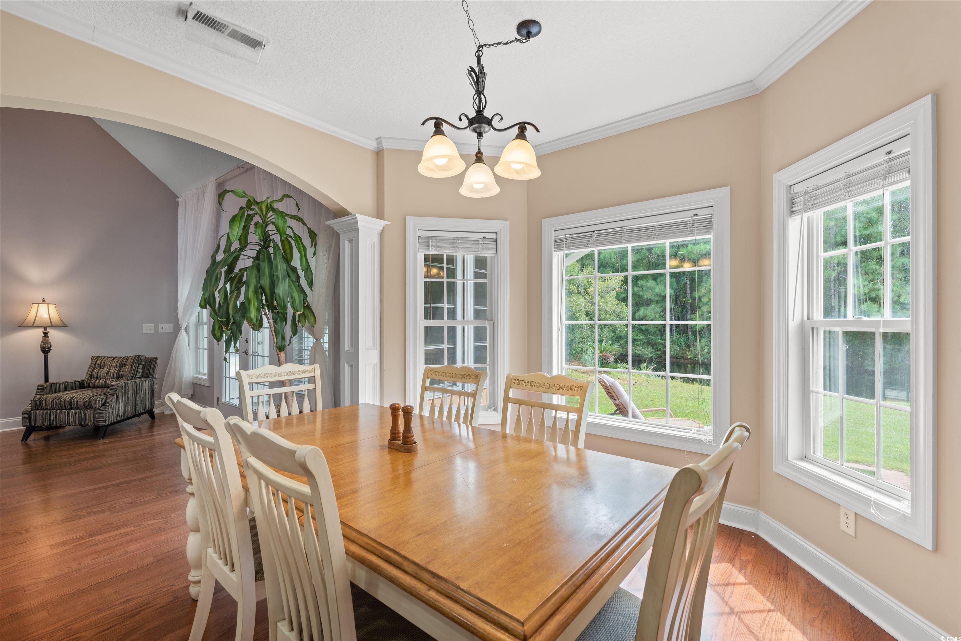 109 Eden Court Murrells Inlet, SC 29576 - Photo 6 of 31 Dining area with arched walkways, ornamental molding, wood finished floors, decorative columns, and a chandelier