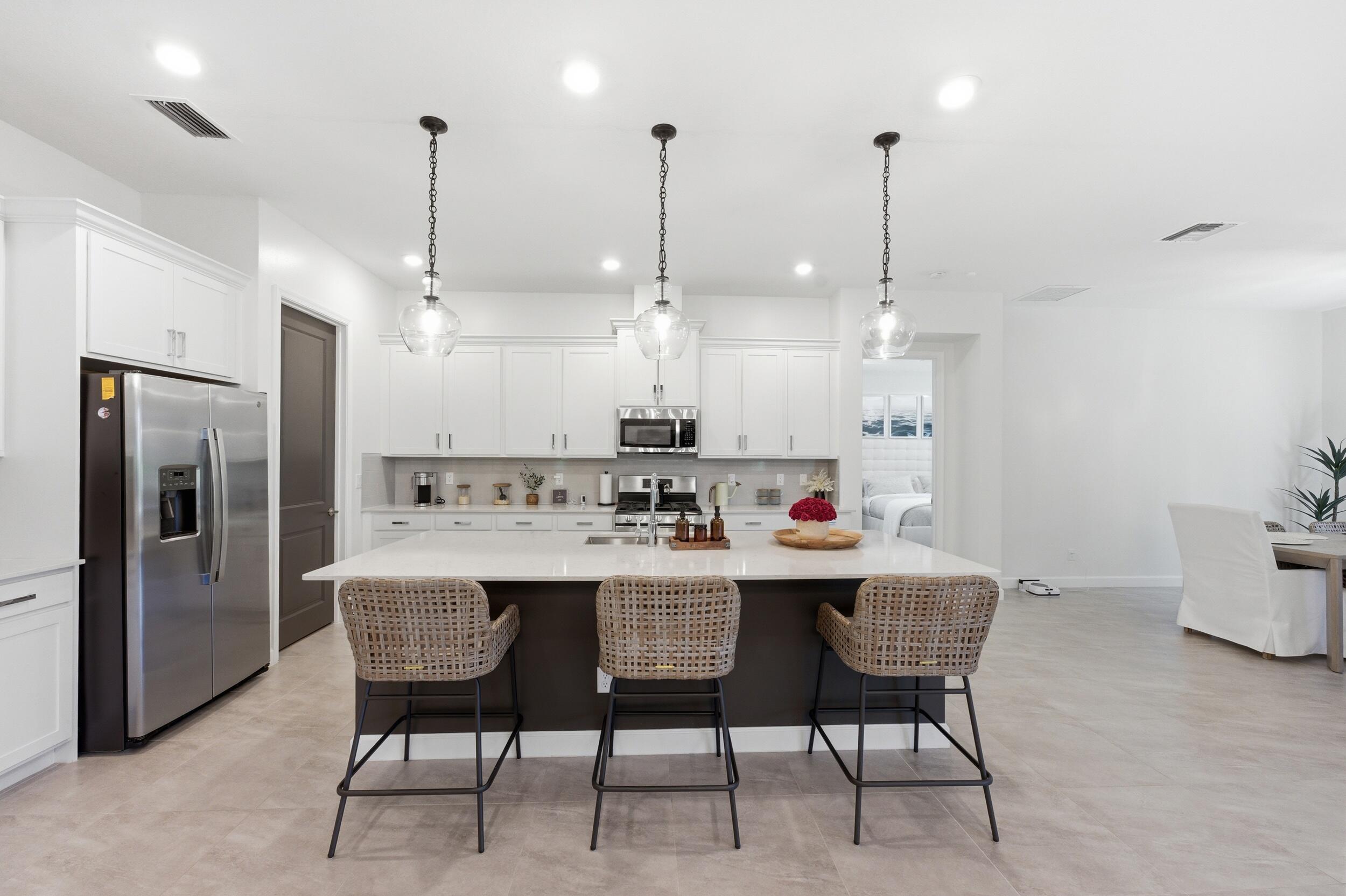 19230 Rolling Acres Road Loxahatchee, FL 33470 - Photo 33 of 58 a kitchen with kitchen island a dining table chairs wooden cabinets and white appliances