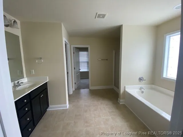 a spacious bathroom with a bathtub sink and mirror