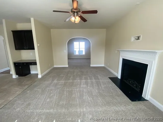 a view of a livingroom with a fireplace a ceiling fan and a fireplace