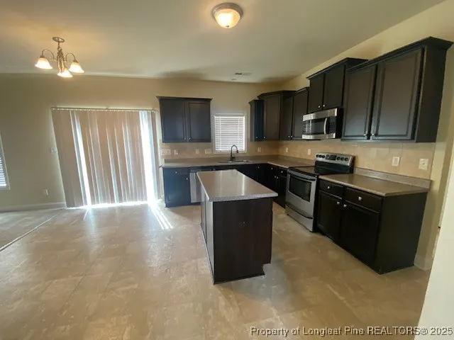 a kitchen with stainless steel appliances granite countertop a stove top oven a sink dishwasher and a microwave oven on the blue kitchen countertops