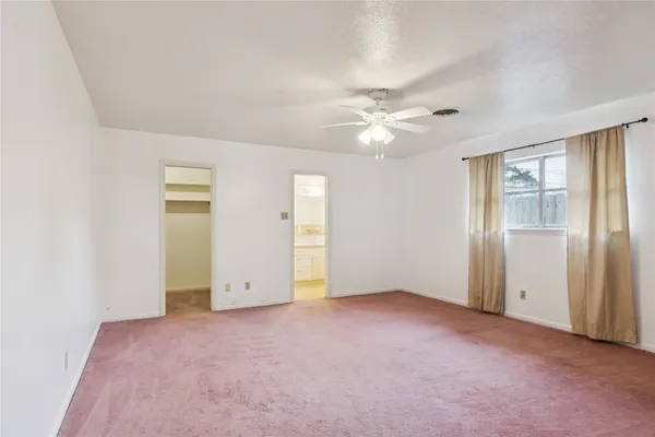 an empty room with closet and a ceiling fan