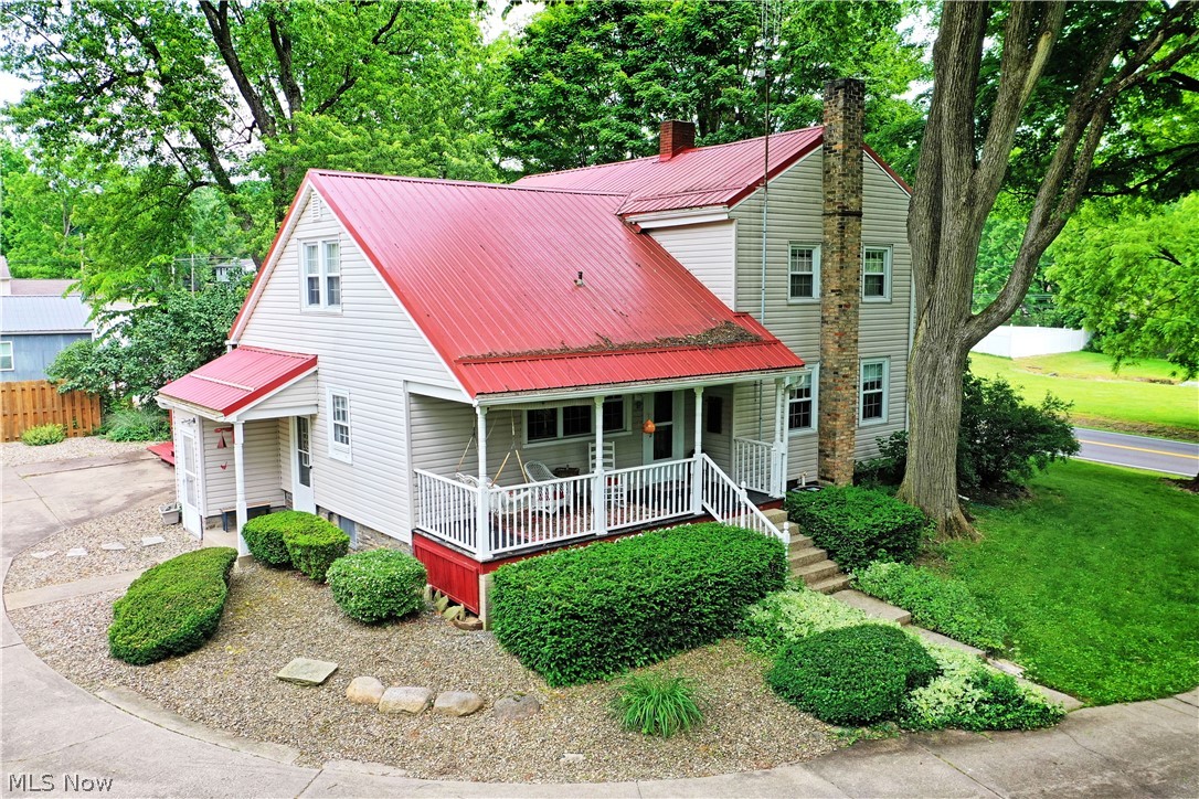 8683 King Graves Road Northeast Warren, OH 44484 - Photo 3 of 50 Traditional-style residence featuring a red metal roof, light-colored siding, and a covered front porch with white railings