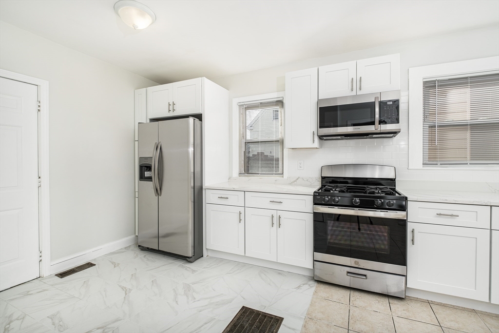a kitchen with stainless steel appliances white cabinets and stove top oven