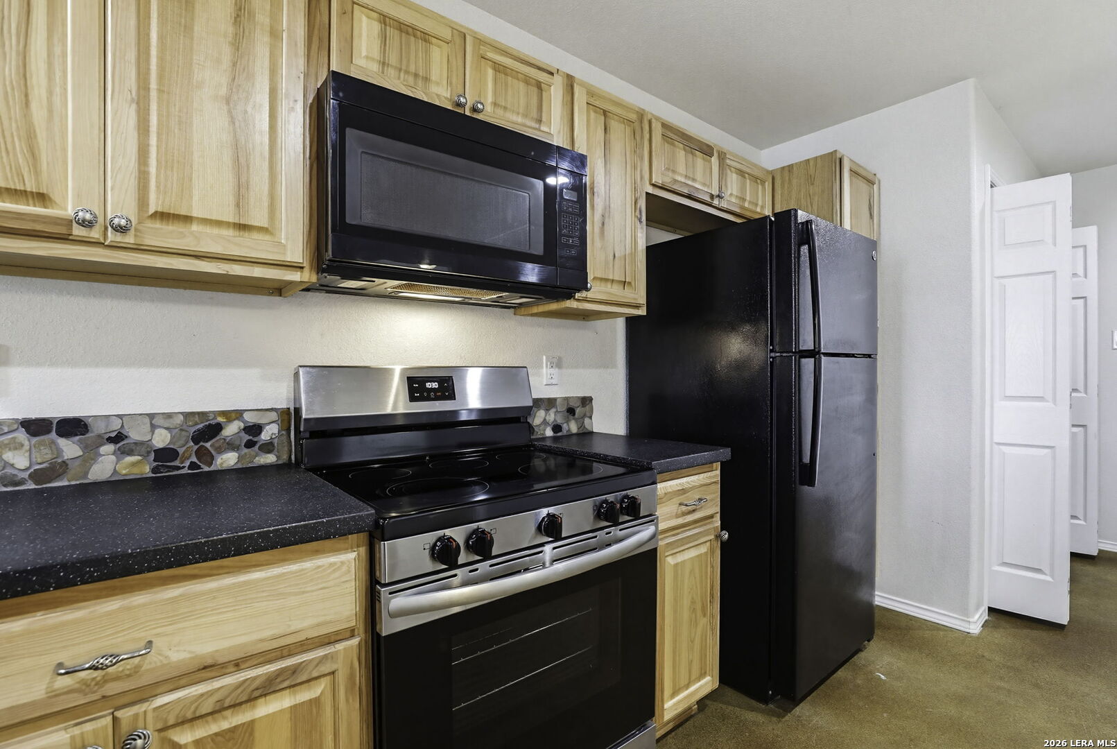 752 Cimarron, Unit B Spring Branch, TX 78070 - Photo 8 of 23 a kitchen with stainless steel appliances granite countertop a stove microwave and refrigerator
