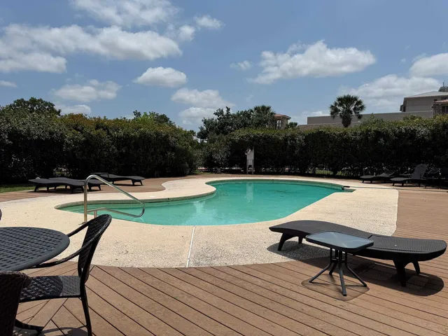a view of swimming pool with seating space and trees in the background