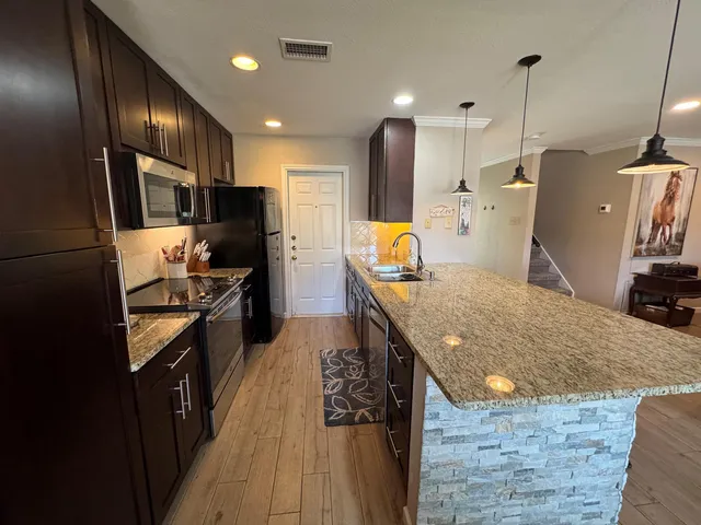 a kitchen with stainless steel appliances granite countertop a refrigerator a stove and a sink