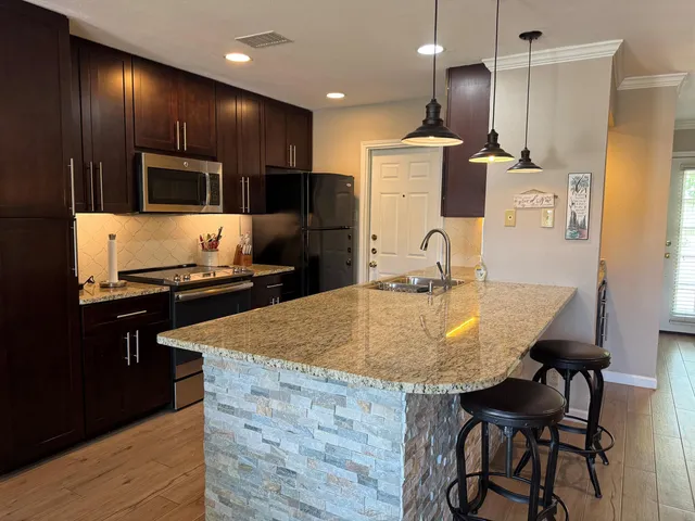 a kitchen with kitchen island granite countertop a sink and a stove