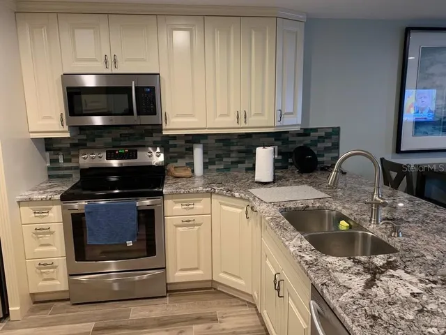 a kitchen with granite countertop a stove and a white cabinets