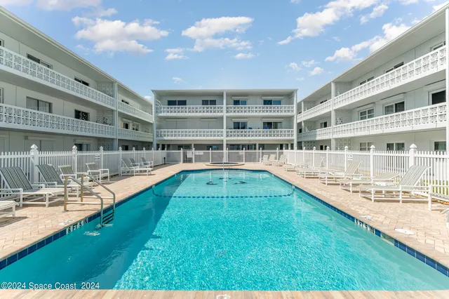 a view of a swimming pool with a lawn chairs and floor to ceiling window