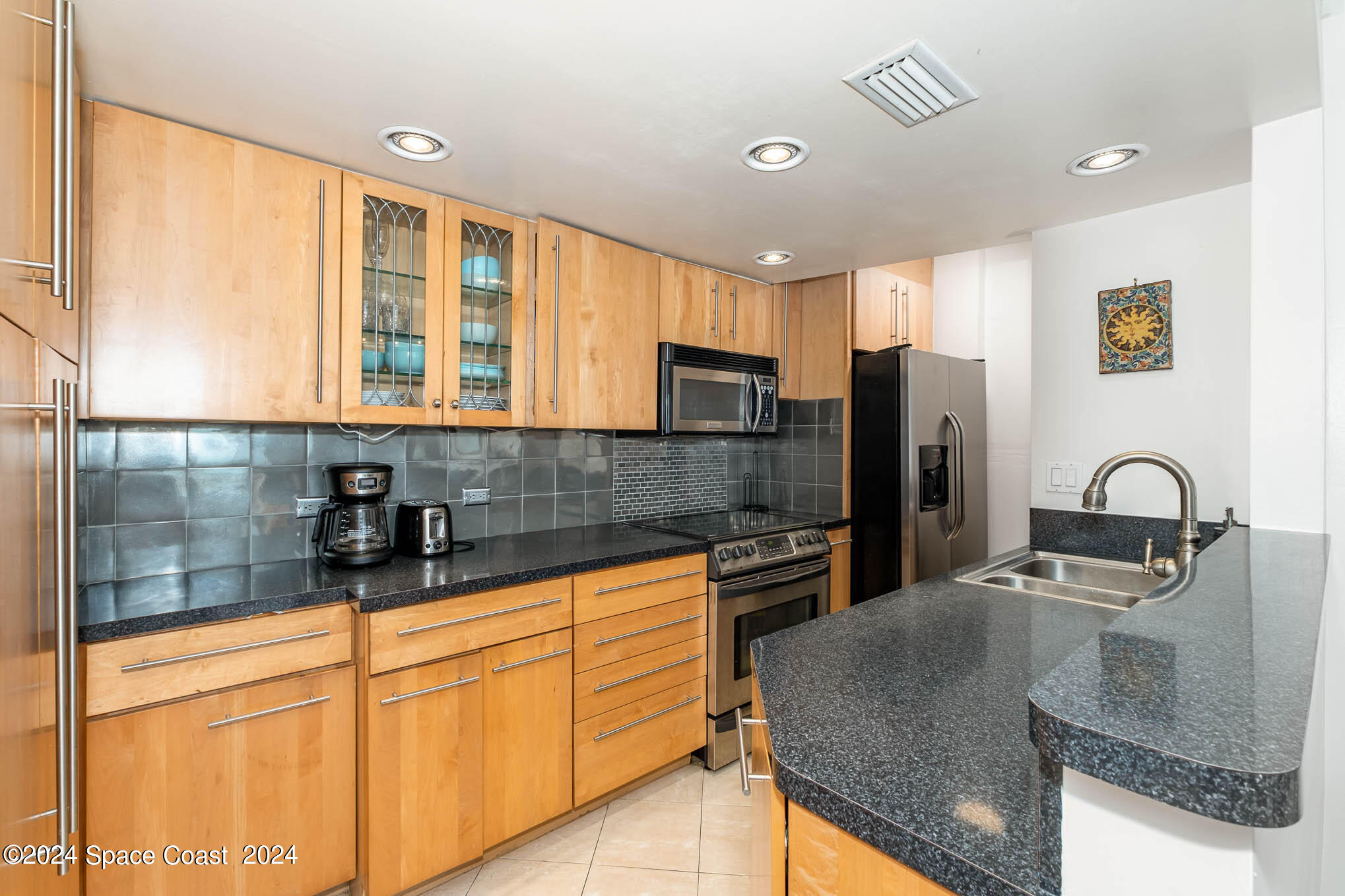 4800 Ocean Beach Boulevard, Unit 311 Cocoa Beach, FL 32931 - Photo 4 of 22 a kitchen with stainless steel appliances granite countertop a sink a stove and refrigerator