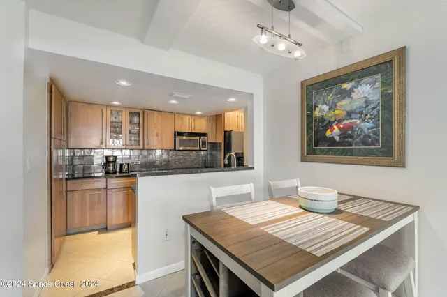 a open kitchen with stainless steel appliances granite countertop a stove top oven a sink a dining table and chairs with wooden floor