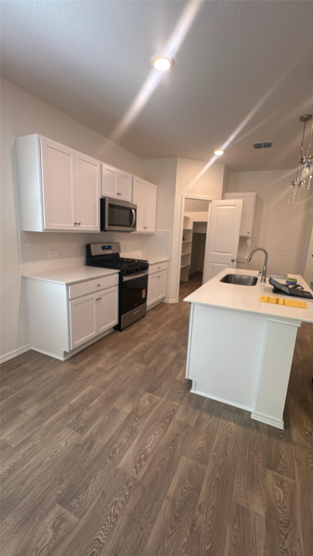 174 Balmorhea Street Kyle, TX 78640 - Photo 2 of 29 Modern kitchen features an island with sink, ample cabinetry, and sleek stainless steel appliances.