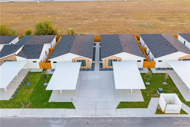 an aerial view of residential houses with outdoor space and ocean view