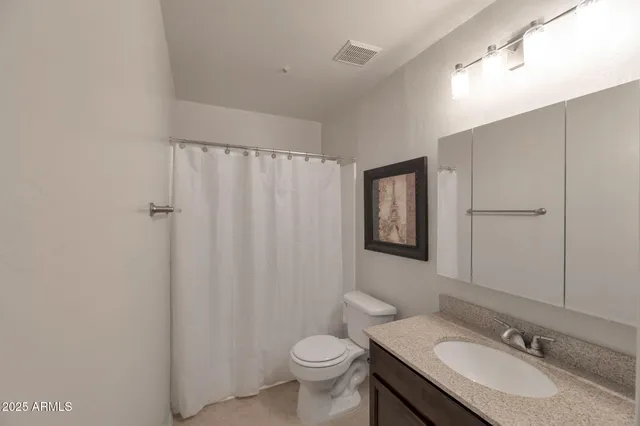 a bathroom with a granite countertop sink toilet and a mirror