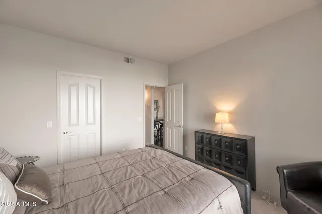 a bedroom with a bed and a lamp on dresser