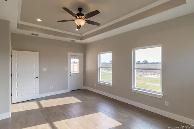 a view of an empty room with a window and a chandelier fan