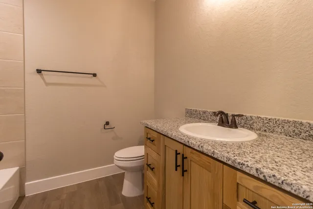 a bathroom with a granite countertop sink and a toilet