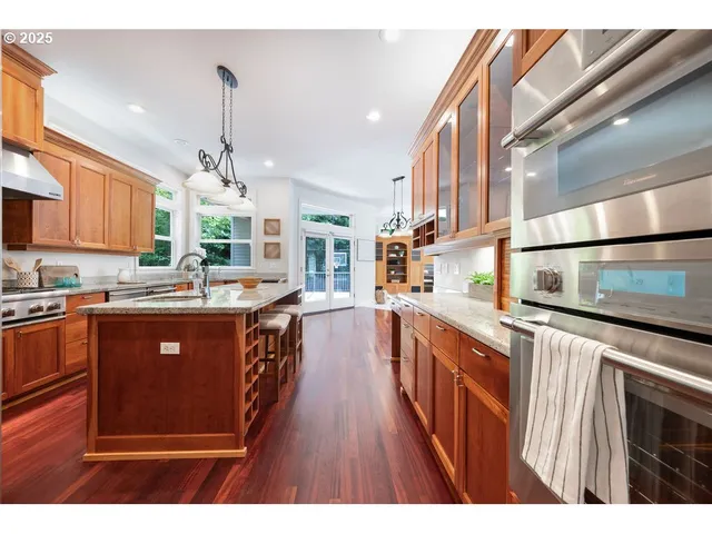 a kitchen with stainless steel appliances granite countertop a sink a stove and a wooden floors