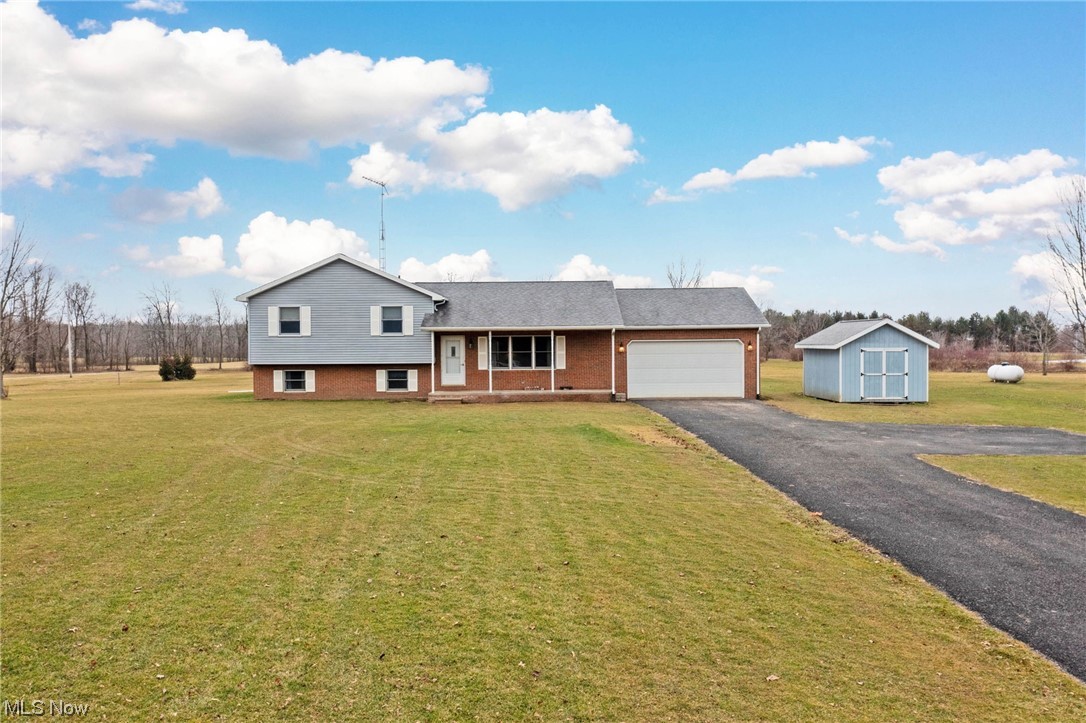411 Adario West Road Shiloh, OH 44878 - Photo 1 of 35 View of front facade with a front lawn, a garage, and a storage shed