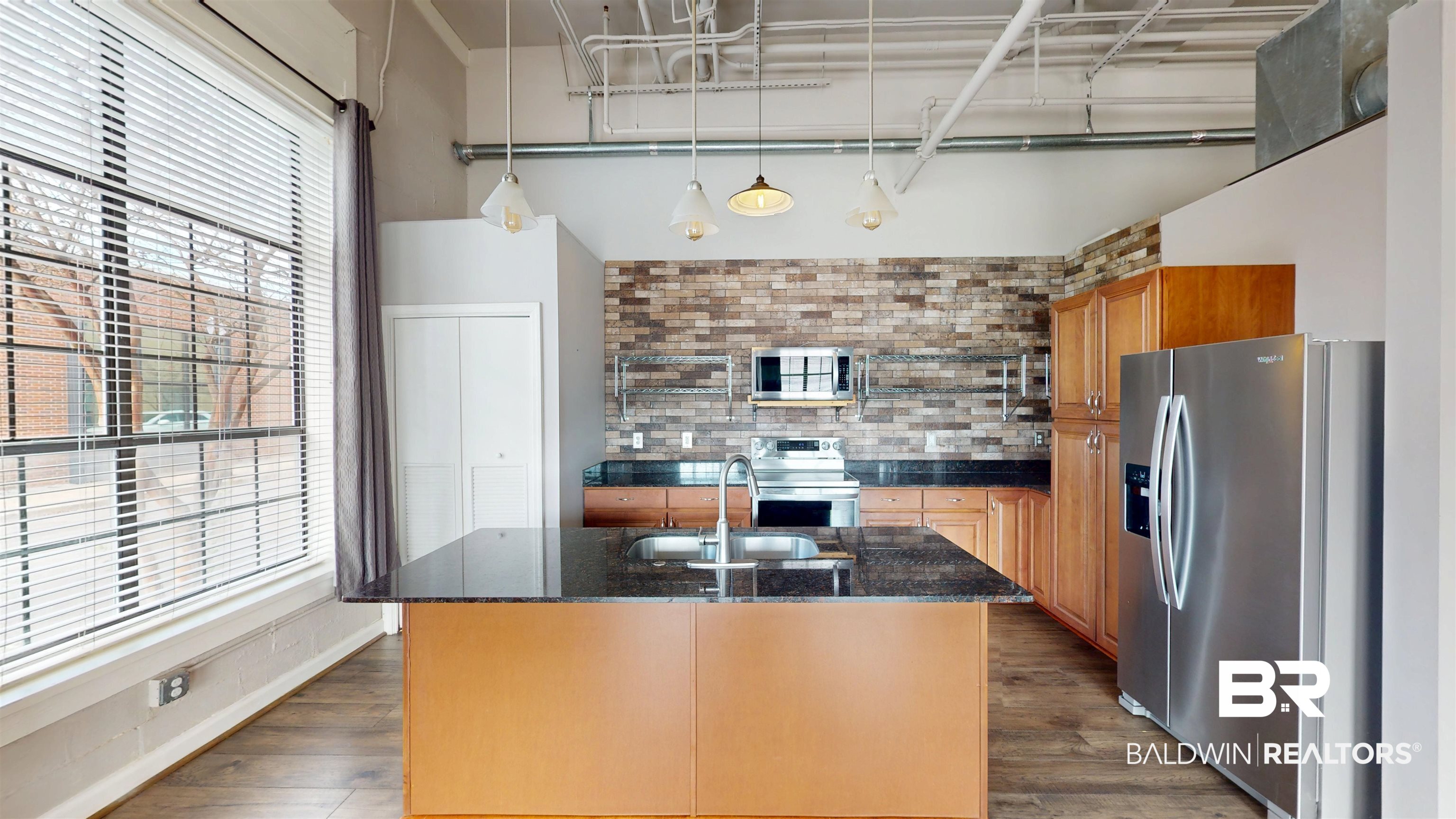 308 St Louis Street, Unit 101 Mobile, AL 36602 - Photo 25 of 30 Kitchen featuring appliances with stainless steel finishes, dark stone counters, dark wood-type flooring, decorative light fixtures, and backsplash