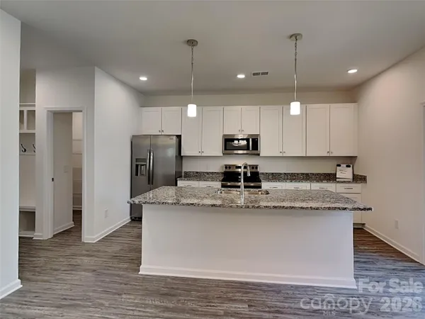 a kitchen with stainless steel appliances granite countertop a sink a refrigerator a microwave and island