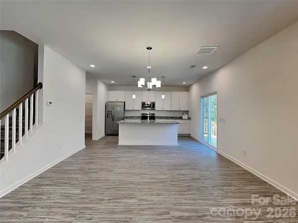 a view of kitchen with kitchen island granite countertop a stove top oven a sink and a chandelier