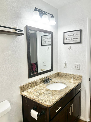 570 250 East Parowan, UT 84761 - Photo 15 of 27 Vanity with a speckled countertop, integrated sink, and dark wood cabinetry