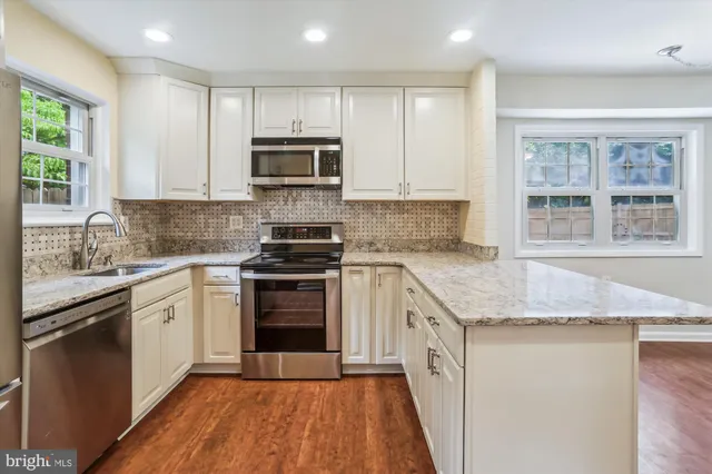 a kitchen with stainless steel appliances granite countertop a stove a sink and a microwave