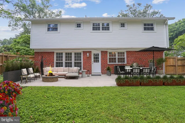 a view of a house with a yard plants and large tree
