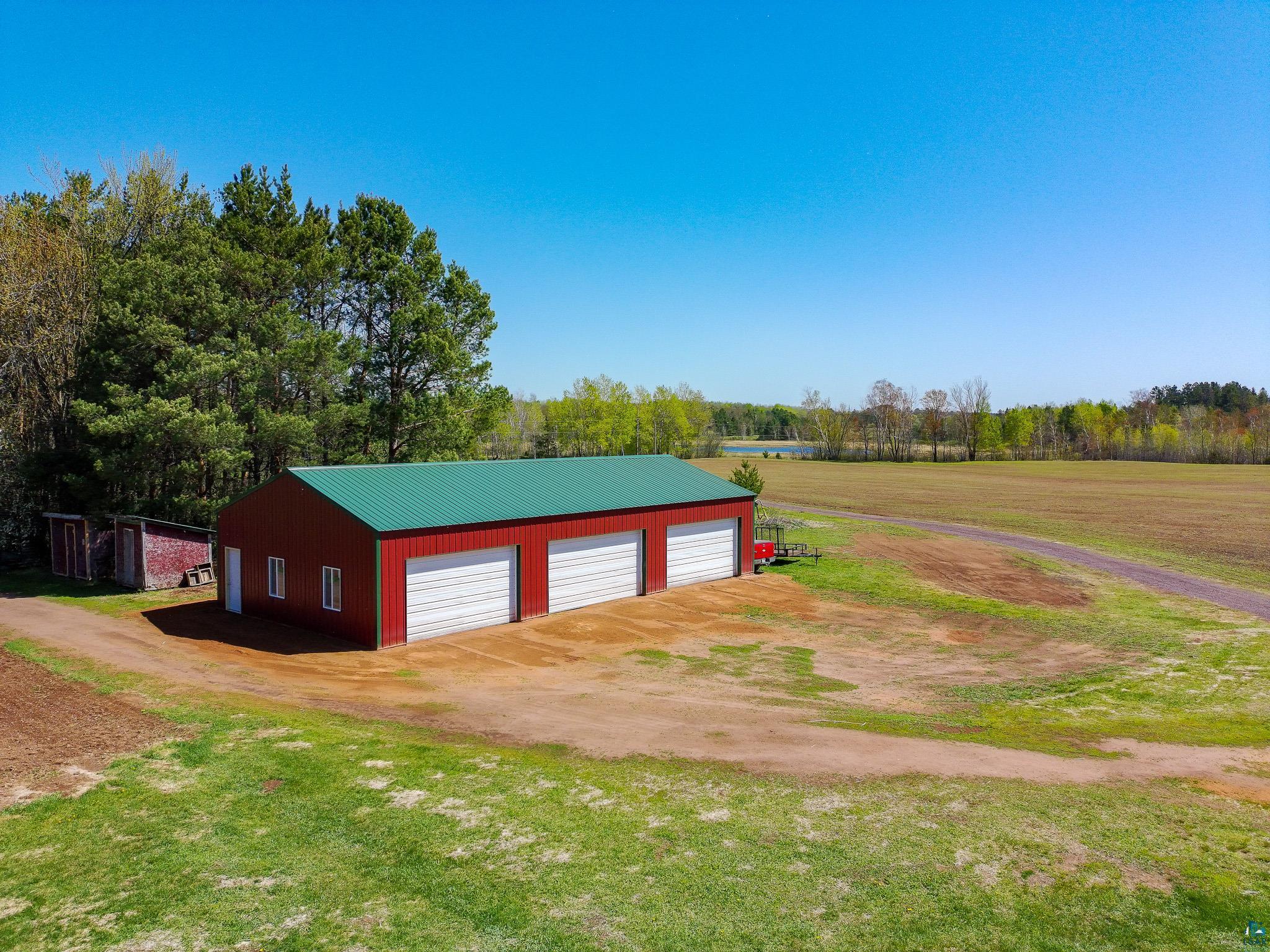 37590 Degerstrom Road Askov, MN 55704 - Photo 36 of 53 Red metal-sided outbuilding featuring a green metal roof and three white garage doors