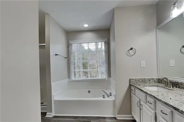 a bathroom with a tub sink and mirror