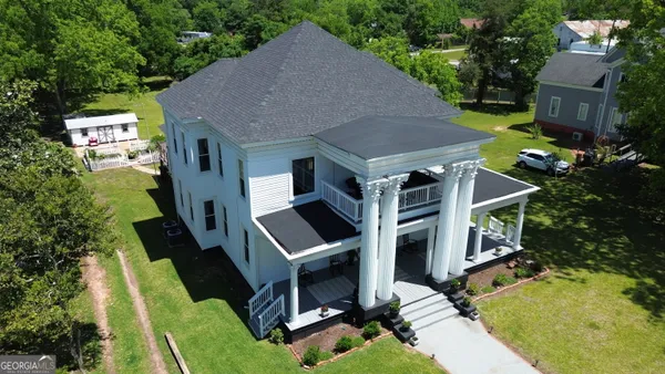 an aerial view of a house with swimming pool and large trees