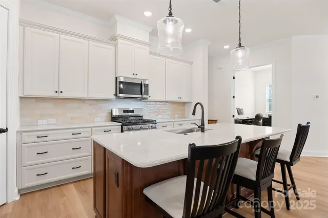 a kitchen with stainless steel appliances kitchen island granite countertop a sink a stove a table and chairs