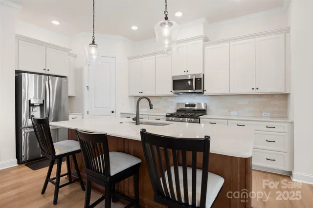 a kitchen with stainless steel appliances granite countertop a sink a stove a refrigerator a dining table and chairs