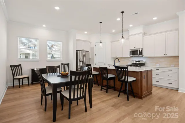 a kitchen with stainless steel appliances kitchen island granite countertop a table chairs and a view of living room