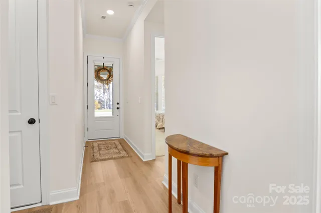 a view of a hallway with wooden floor and a bathroom