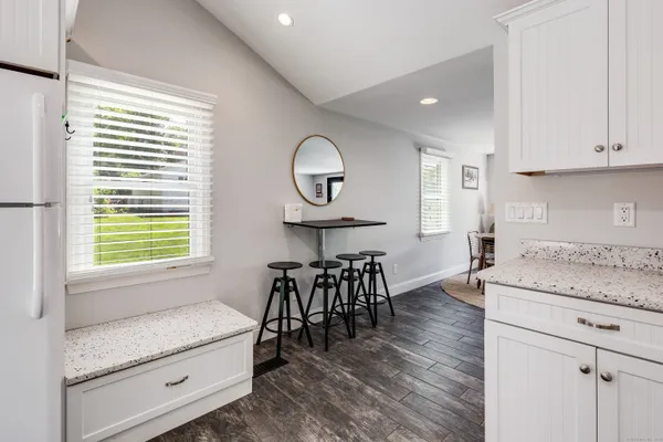 a kitchen with granite countertop a table chairs a sink dishwasher and cabinets with wooden floor