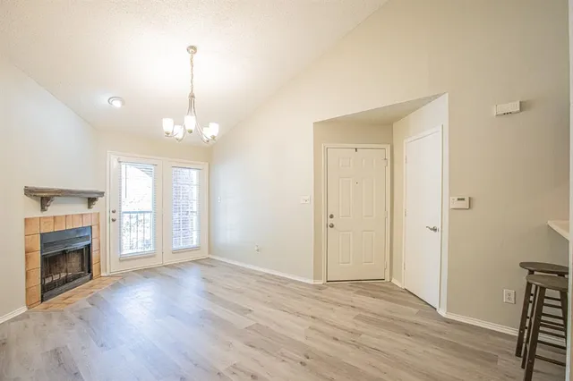 a view of an empty room with wooden floor fireplace and a window