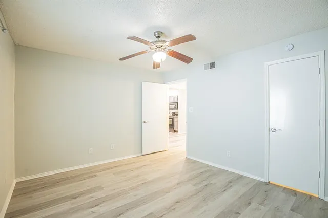an empty room with wooden floor fan and windows