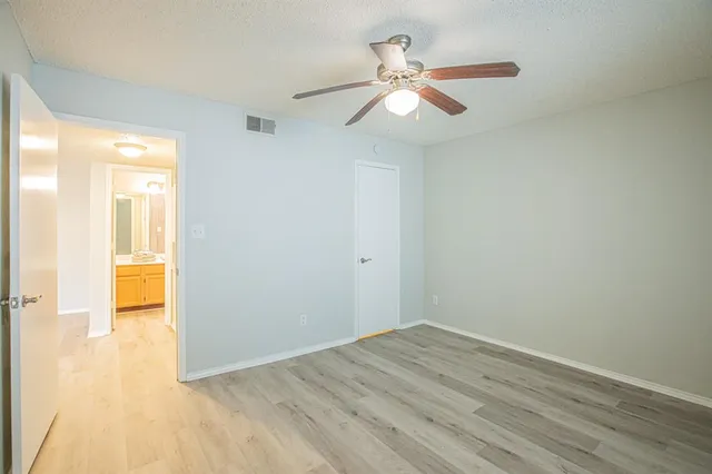 an empty room with wooden floor fan and windows