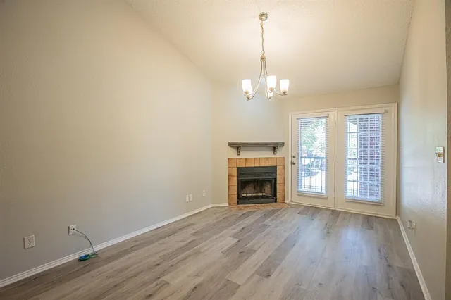 a view of empty room with wooden floor and kitchen view