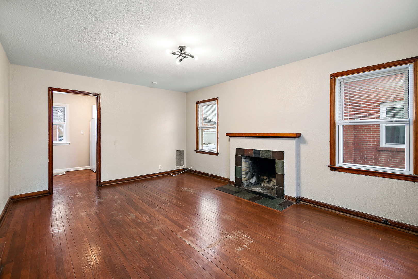 381 South Nelson Avenue Kankakee, IL 60901 - Photo 9 of 15 an empty room with wooden floor fireplace and windows
